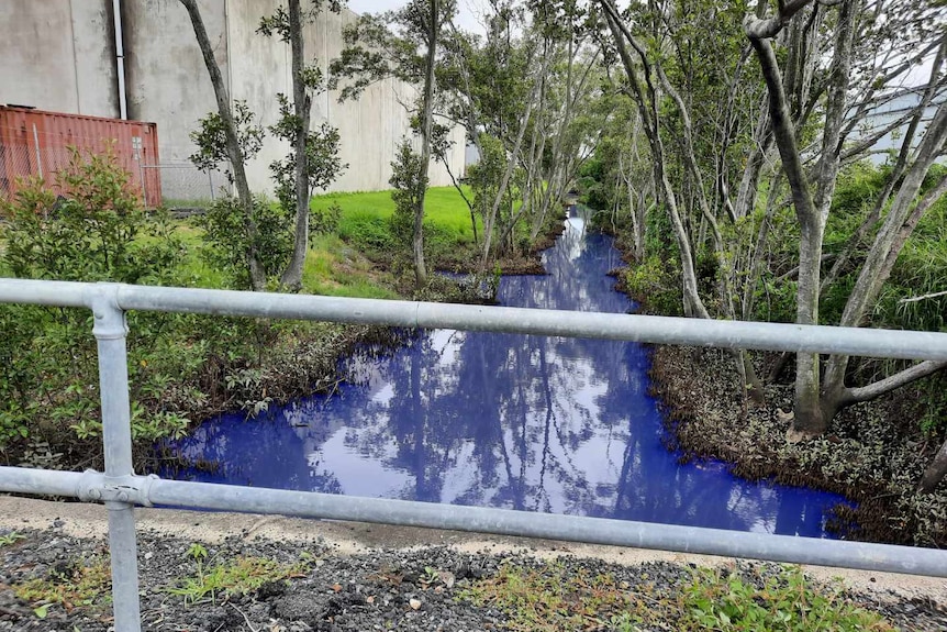a small creek in an industrial area with blue water