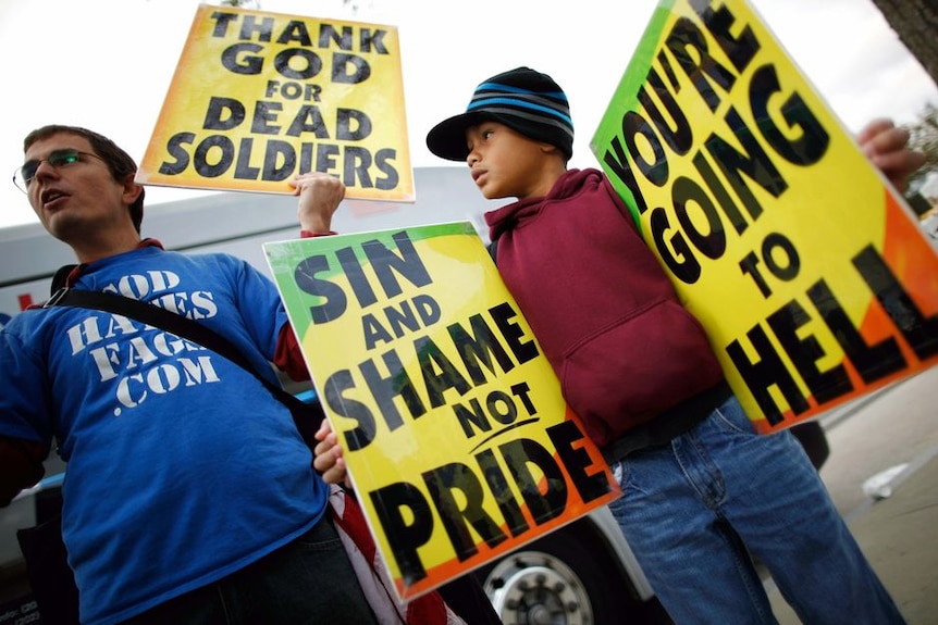 A man and a boy from Westboro Baptist Church hold placards at a protest outside the US Supreme Court. October 6, 2010. (AAP)