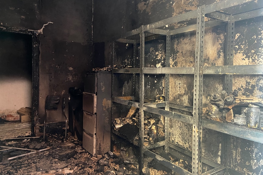 Soot covered walls of a burnt room with empty shelves, everything destroyed