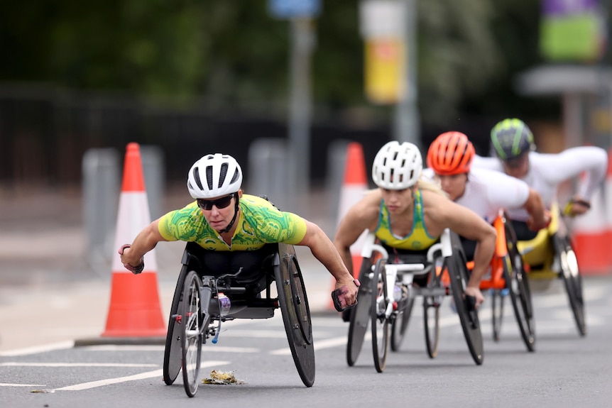 Women wheelchair racers compete in an event on the road