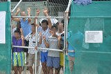March 21, 2014 file image of Asylum seekers staring at media from behind a fence at the Manus Island detention centre, Papua New Guinea