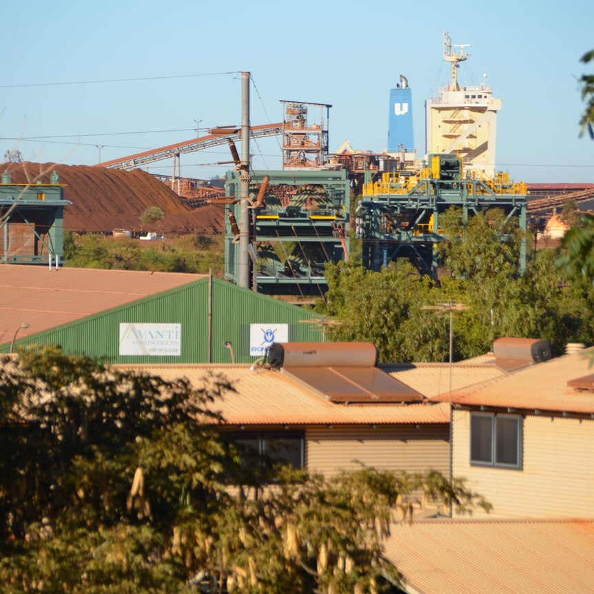 A look across a suburb with houses towards a shipping facility in the background.