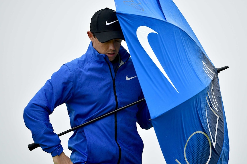 Rory McIlroy shields himself with an umbrella
