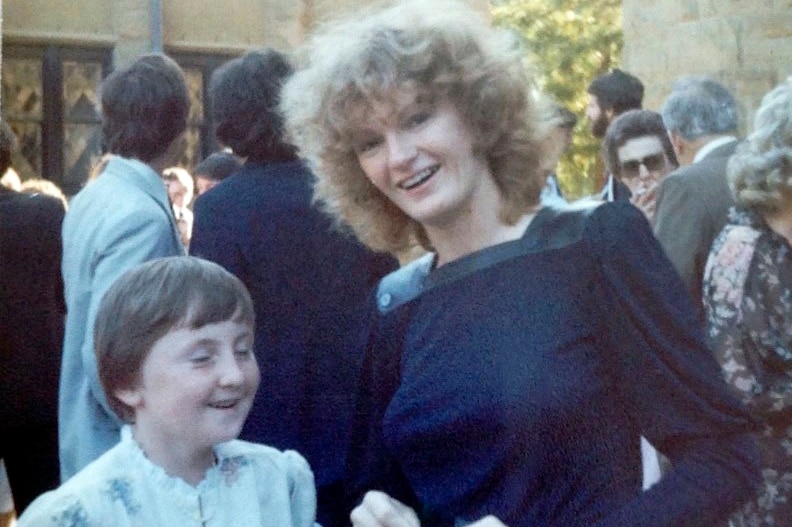 Rhonda Favaloro with curly blond hair wearing a navy dress.