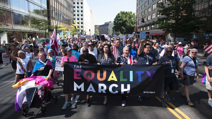 LGBT rights supporters march in Washington carrying a large sign that reads 'The Equality March'