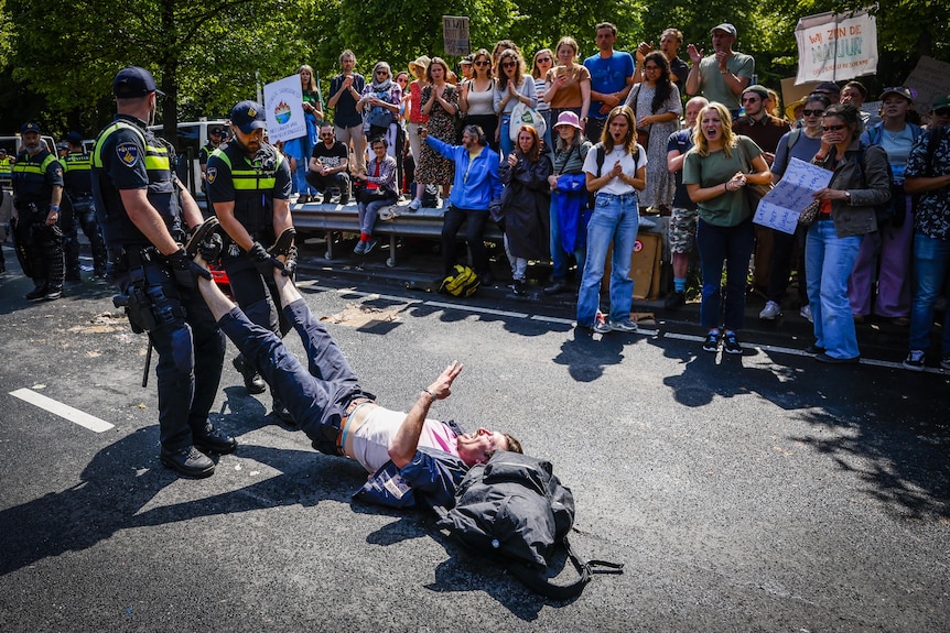 Police drag a man by the feet as he makes a peace gesture.