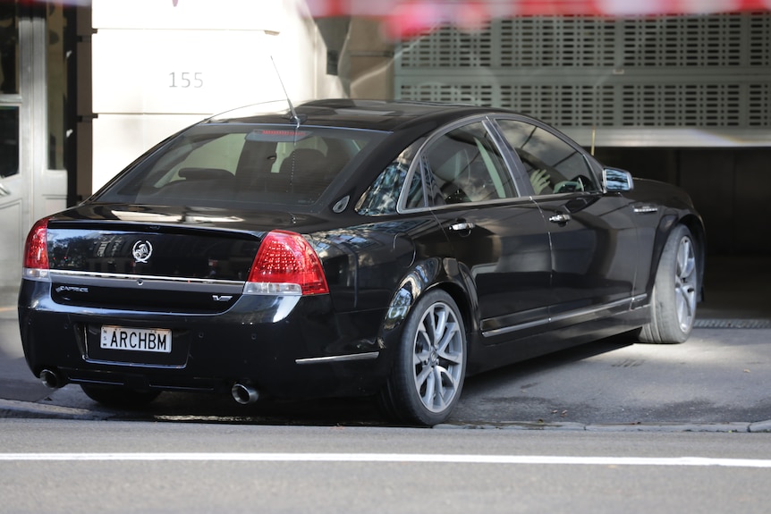 A black car drives into a carpark.