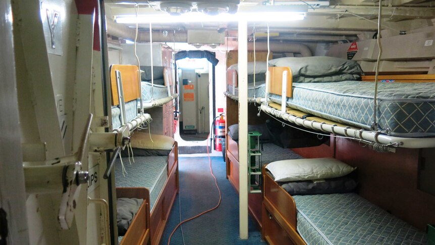 Bunk beds on either side of a narrow corridor in the ship