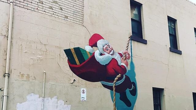A mural of Santa climbing a wall with a rope.