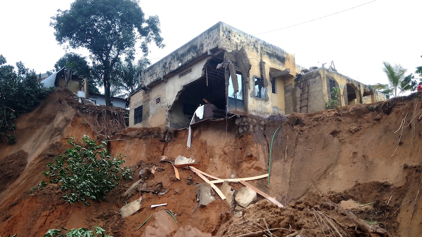 A destroyed house on the side of a cliff that has been washed away by water. 