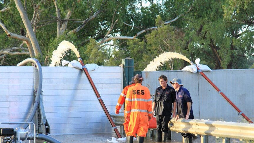 SES and council workers monitor pumps at a levee gate in Charleville