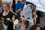 A woman holds up a poster about child asylum seekers.