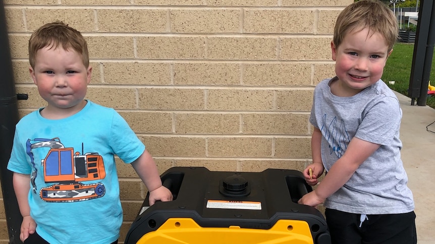 Two children standing next to a power generator