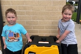 Two children standing next to a power generator