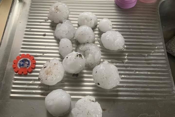 A handful of large hailstones sit on a kitchen bench.