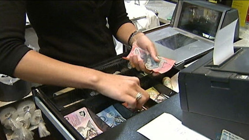 Shop assistant takes money from cash register.