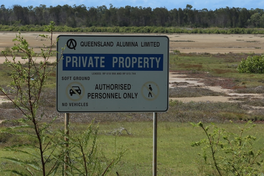 A sign in a field that says Queensland Alumina Limited PRIVATE PROPERTY