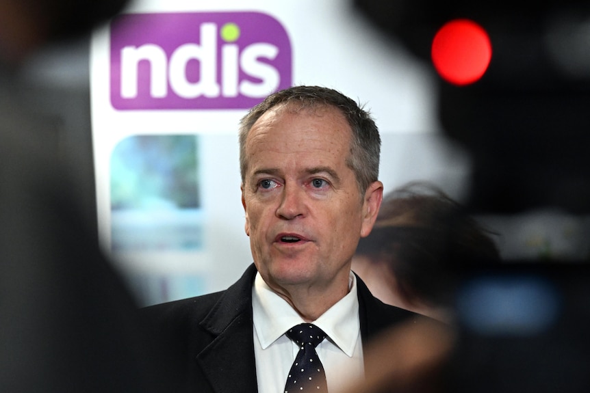 Bill Shorten standing in front of a NDIS logo