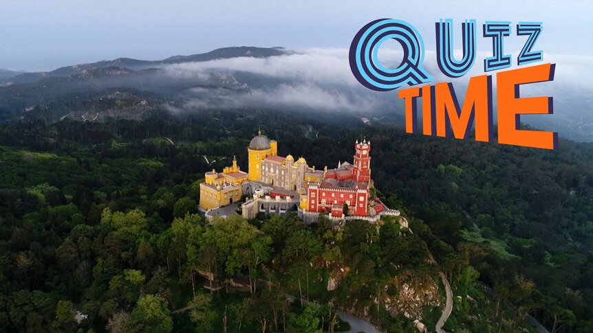 An aerial view of the brightly coloured National Palace of Pena in Portugal which sits a top a hill surrounded by woodland.