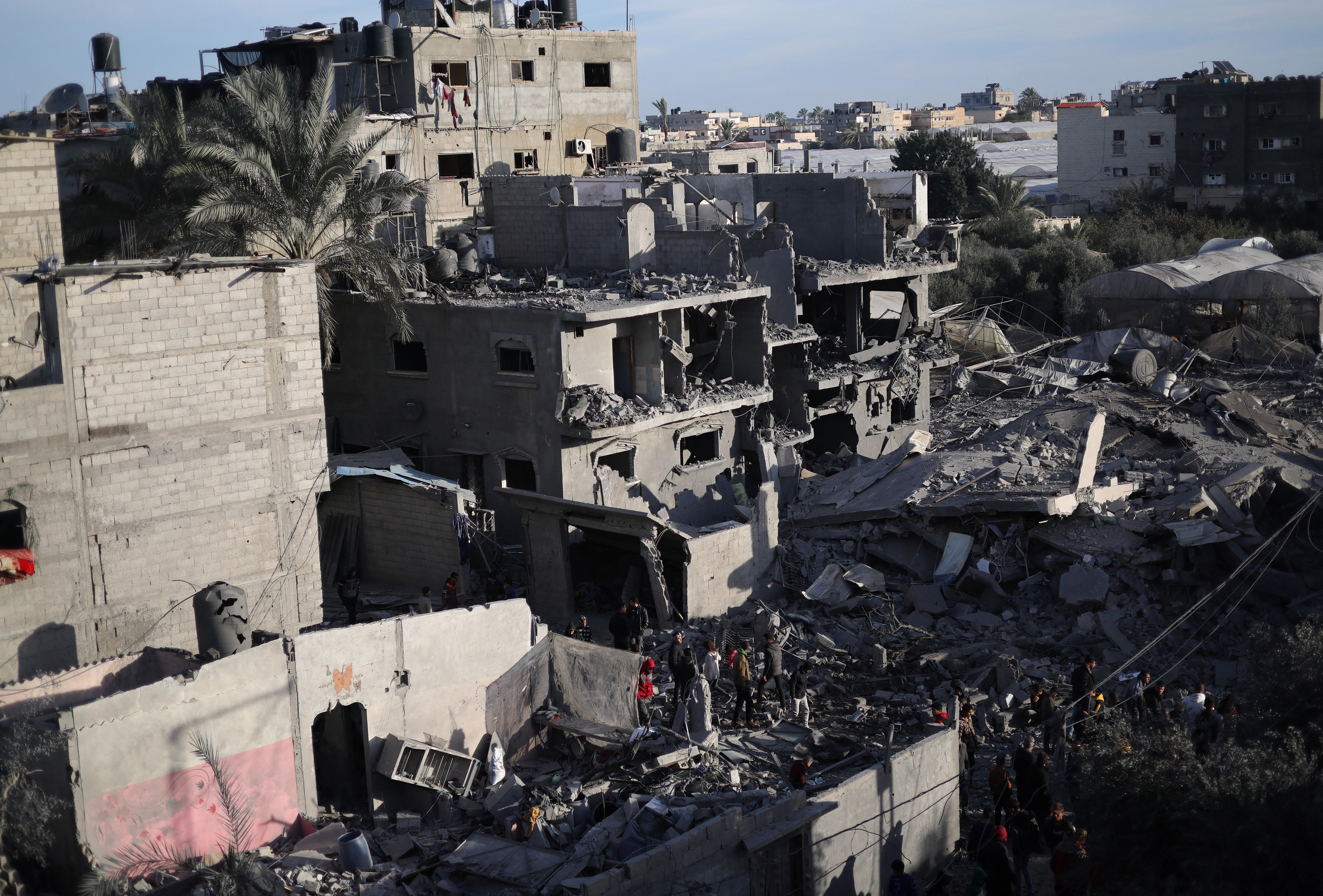 A damaged building in Rafah, rubble and debri being combed thorgh by people