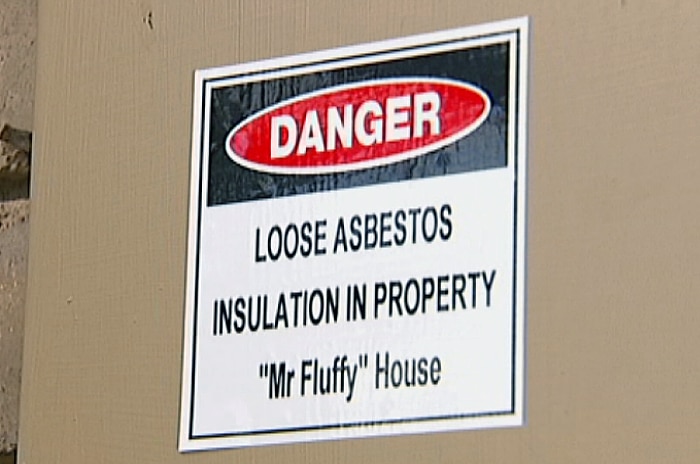 Sign on fuse box identifying a house as a Mr Fluffy loose-fill asbestos home.