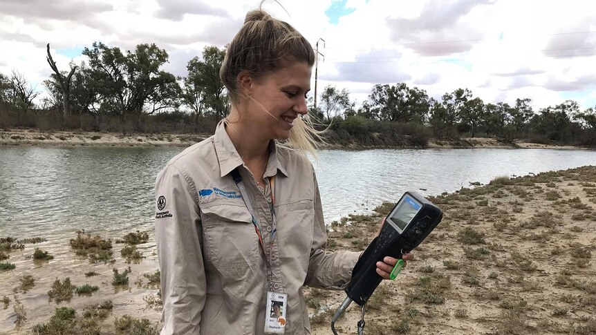 Woman holding testing equipment with Riverland lagoon behind her
