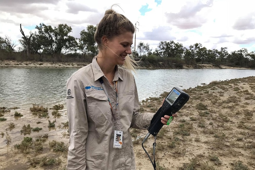 Woman holding testing equipment with Riverland lagoon behind her