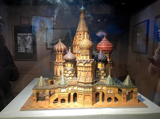 An intricate matchstick model of a cathedral in a glass display case.