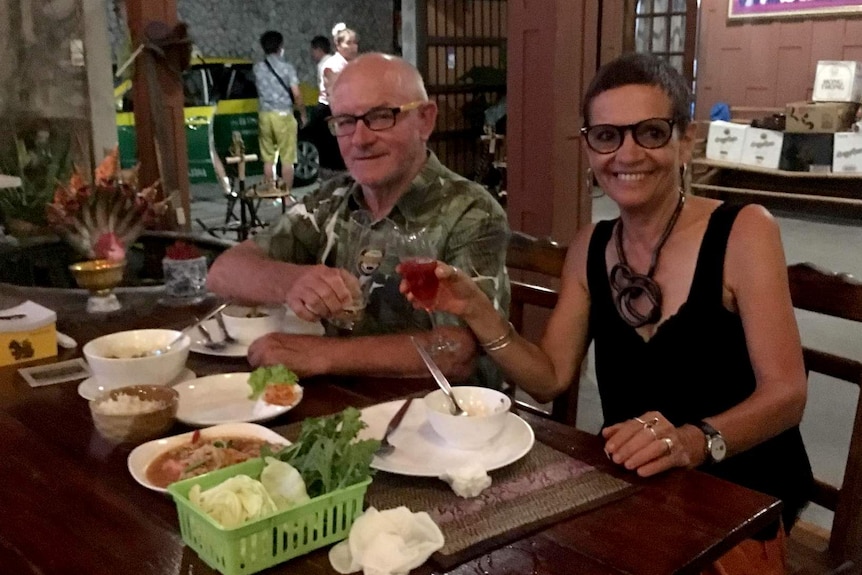 A couple sitting at a restaurant inside the open door of a restaurant.