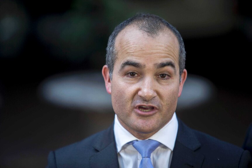 James Merlino wears a suit and tie.