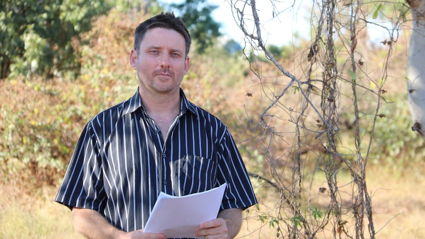 Environmentalist Martin Pritchard holds some documents while standing in the bush.