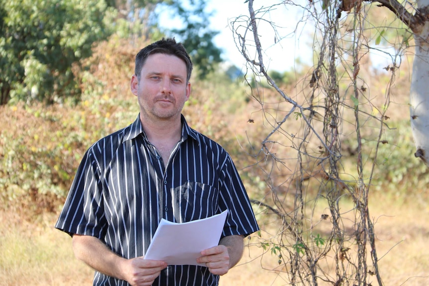 El ambientalista Martin Pritchard sostiene algunos documentos mientras está parado en el monte.
