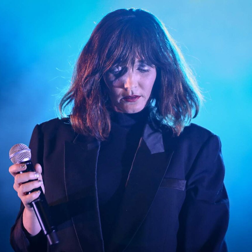 Australian musician Sarah Blasko holding a microphone on stage
