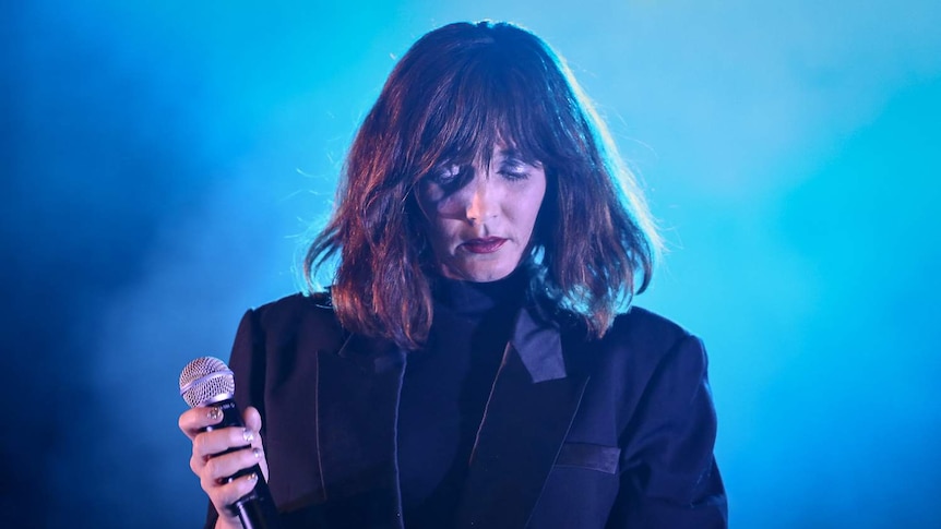 Australian musician Sarah Blasko holding a microphone on stage