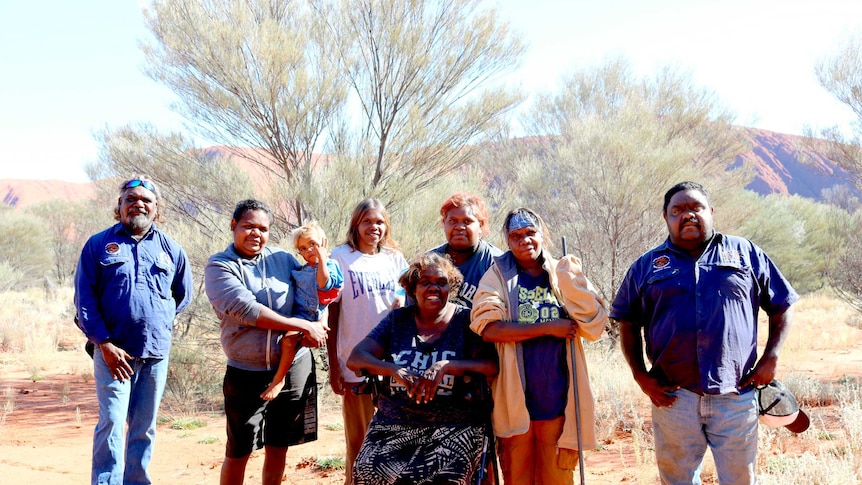 Docker Rangers and Mutitjulu women stand in front of Uluru