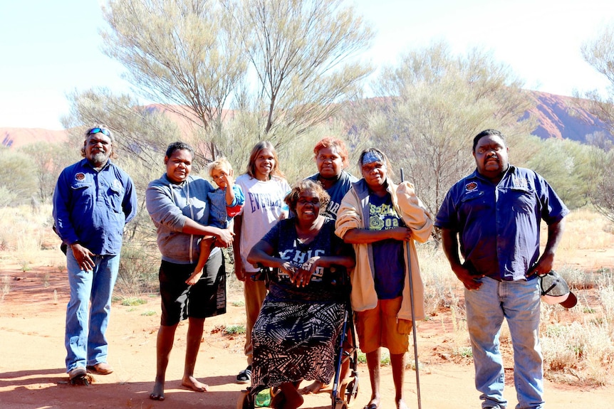 Docker Rangers and Mutitjulu women stand in front of Uluru