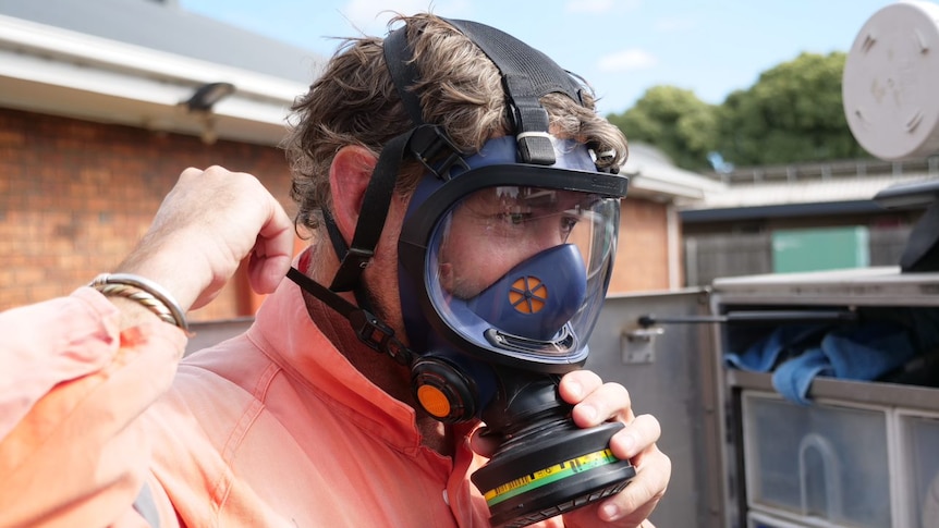 A man in a gas mask and hi-vis