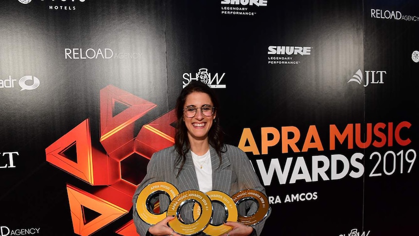 Songwriter Sarah Aarons holding four APRA music awards