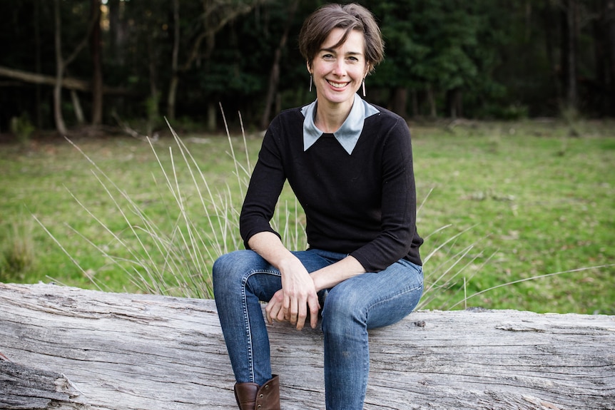 Cressida Cains sits on a log.