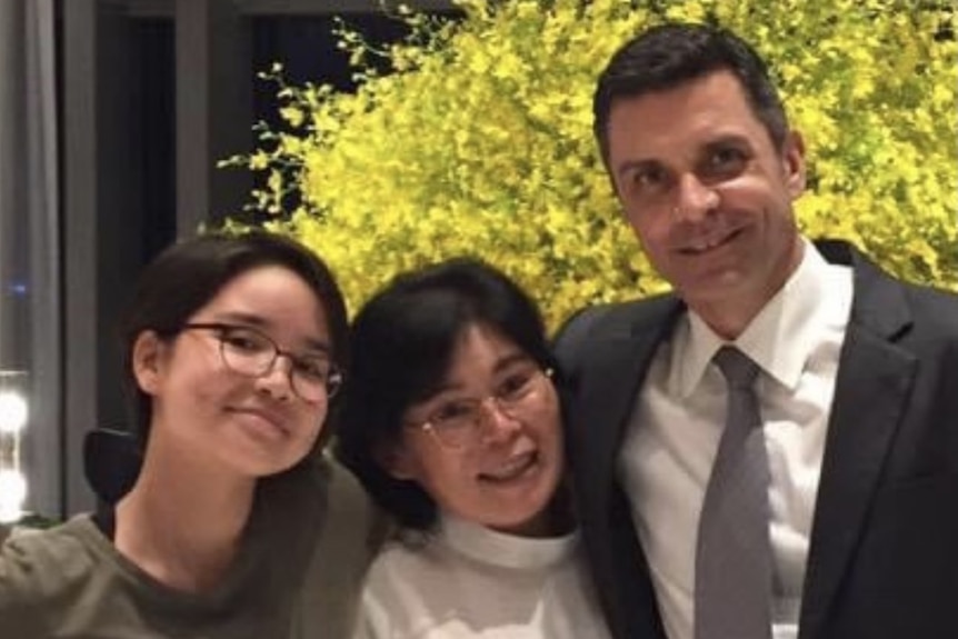 A man standing next to his wife and daughter. 