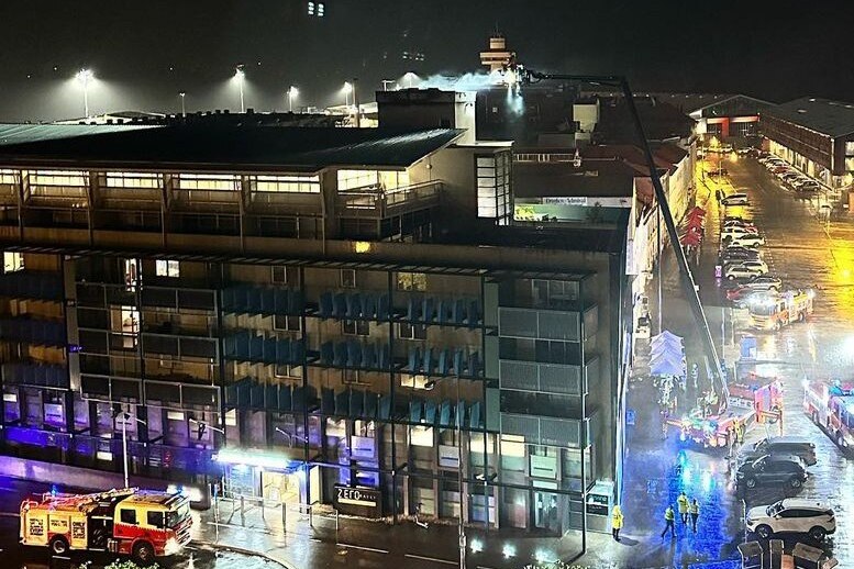 Firefighters train water on the top of an apartment building at night