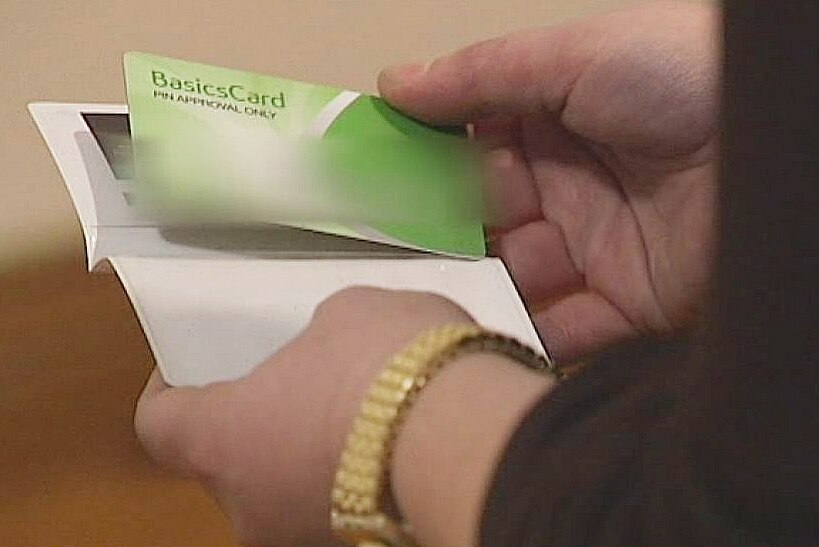 A woman holds a green, purse-sized card with the words 'basic card' on it.