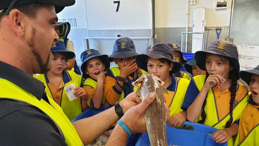 School children gasp at the sight of a fresh fish as a fishermen's co-op