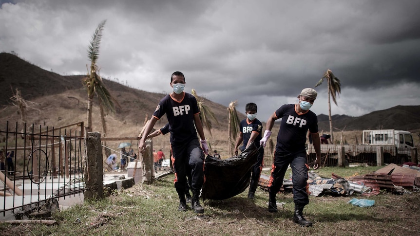 Firemen carry corpses of typhoon victims