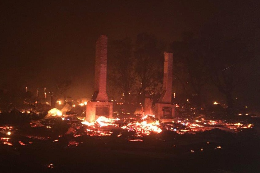 Flames smoulder on the ground and light the night sky as two chimney stacks stand amid the rubble of Yarloop.