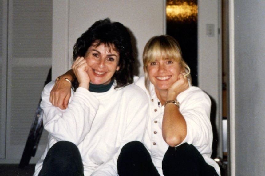 Two smiling women, one dark-haired and the other blonde.