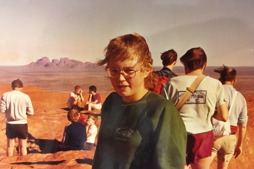 A young woman in an outback setting wearing glasses