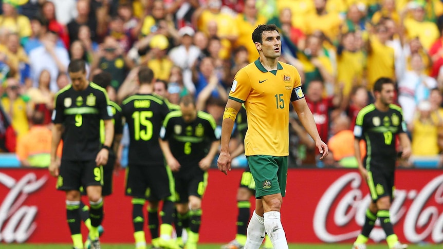 A dejected Mile Jedinak of Australia looks on after Spain score.