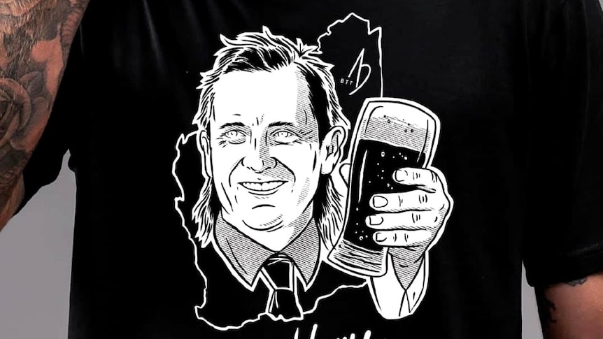 A man wearing a black t-shirt with a cartoon image of Mark McGowan drinking a beer and the words 'ya welcome' written on it.