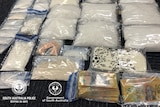 Drugs and cash in plastic bags laid out on a floor.